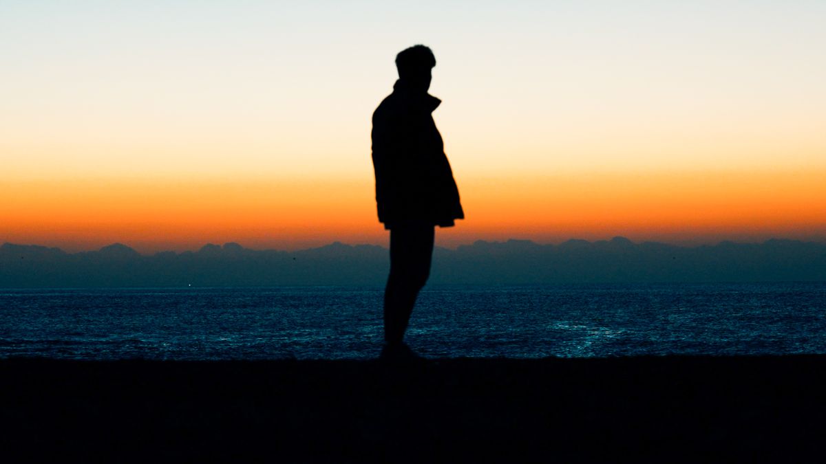 夕暮れの海岸に立つ人物のシルエット