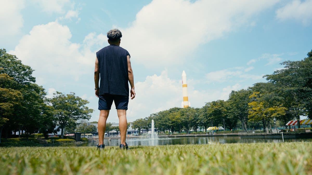まつりつくば会場でロケットのモニュメントを背に立つ人物の後ろ姿